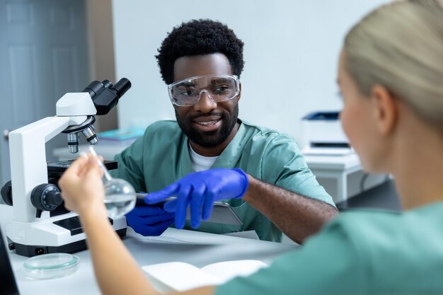 Multicultural médica mulher e homem trabalhando em laboratório discutindo pesquisa e analisando resultados de testes