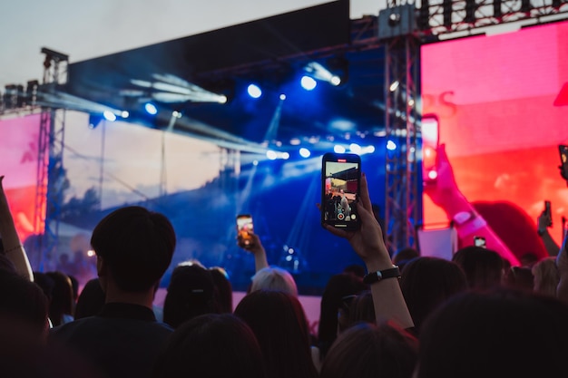 multidão de pessoas no palco em um concerto de música ao vivo estão filmando vídeos em smartphones em suas mãos