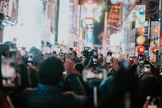 Multidão fotografando na rua iluminada à noite