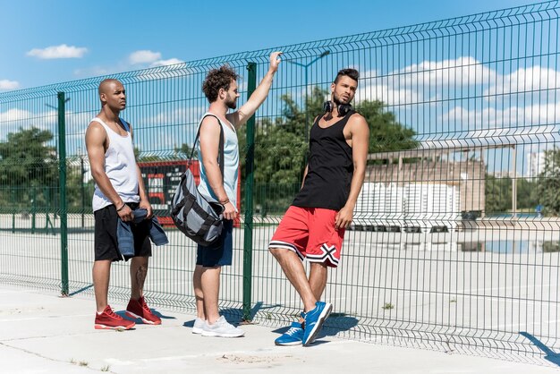 Multiethische Gruppe von Basketballspielern, die sich nach dem Spiel auf dem Platz ausruhen