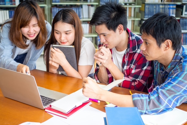 Multiethnische College-Studenten, die Testergebnisse überprüfen und Laptop-Bildschirm in Bibliothek betrachten.