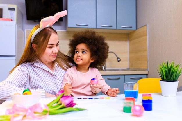 Multiethnische Familie bereitet sich auf die Osterveranstaltung in der Küche vor, die Eier malt