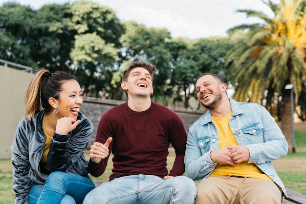 Multiethnische Freunde haben Spaß am Sitzen im Park