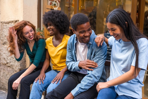 Multiethnische Freunde in einem Café, die in der Tür des Schaufensters sitzen und viel lachen