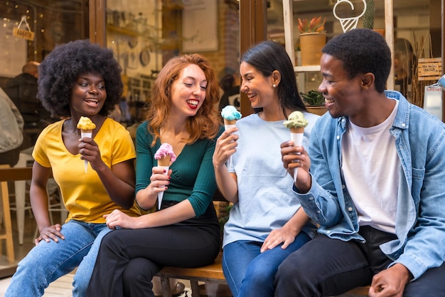 Multiethnische Freunde sitzen in einer Eisdiele und essen ein Eis und lachen viel