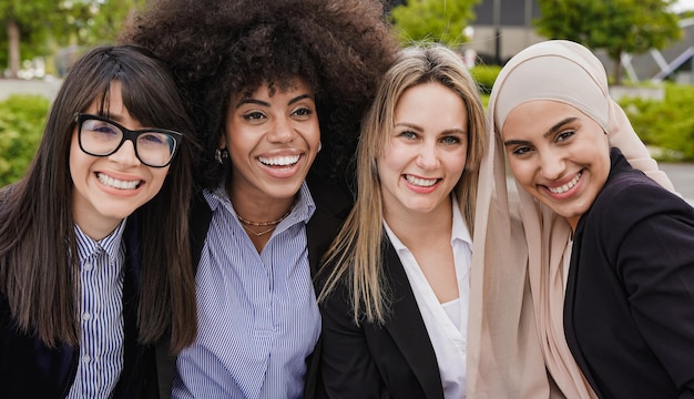 Multiethnische Geschäftsfrauen lächeln während der Mittagspause außerhalb des Büros vor der Kamera