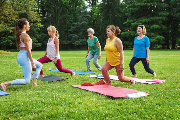 Multiethnische Gruppe älterer Frauen, die im Park mit Fitnesstrainer trainieren - Aktive ältere Menschen, die Sport in der Natur treiben