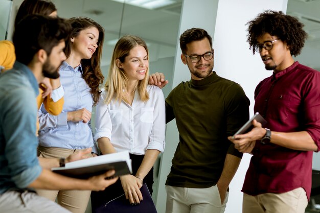 Multiethnische Gruppe junge Leute, die im modernen Büro und im Brainstorming stehen