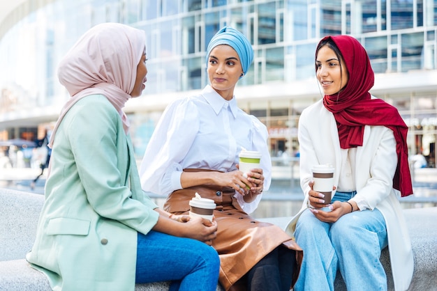 Multiethnische Gruppe muslimischer Mädchen, die Freizeitkleidung und traditionelle Hijab-Bindung tragen und Spaß im Freien haben - 3 arabische junge Mädchen