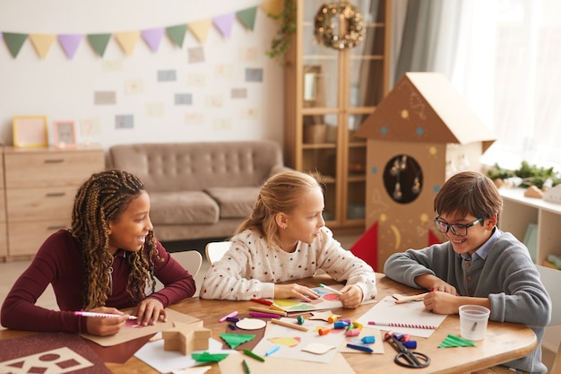 Multiethnische Gruppe von Kindern, die Bilder zusammen zeichnen, während sie Kunst- und Handwerksunterricht genießen, Raum kopieren