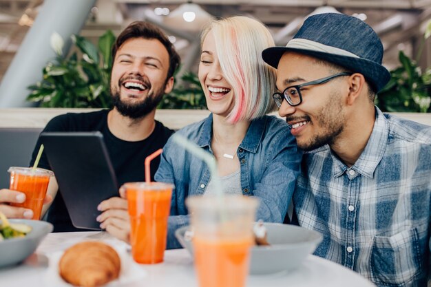 Multiethnische Kollegen, die Tablette am Kaffeetisch verwenden