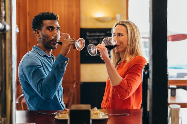 Multiethnische Paare sehen sich mit Gefühl an, während sie in einem Restaurant Rotwein aus ihren Gläsern trinken
