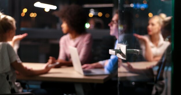 Multiethnisches Startup-Business-Team beim Treffen im modernen Nachtbüro, Brainstorming, Arbeiten am Laptop