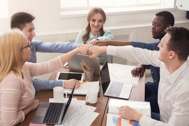 Multiethnisches Team stellt Hände zusammen, verbindet, Teambuilding und Allianzkonzept. Menschen im Büro vereinen sich für Teamwork und Zusammenarbeit, kopieren Raum