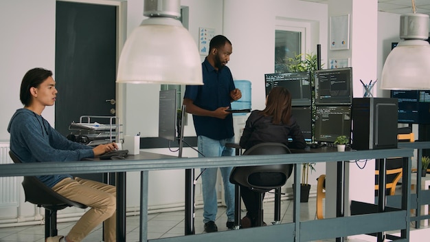 Multiethnisches Team von App-Entwicklern, die an einem Gruppenprojekt zusammenarbeiten, Algorithmus für eine neue Cloud-Computing-Benutzeroberfläche auf dem Computer. Vielfältiges Team von Softwareentwicklern beim Brainstorming von Code-Ideen.