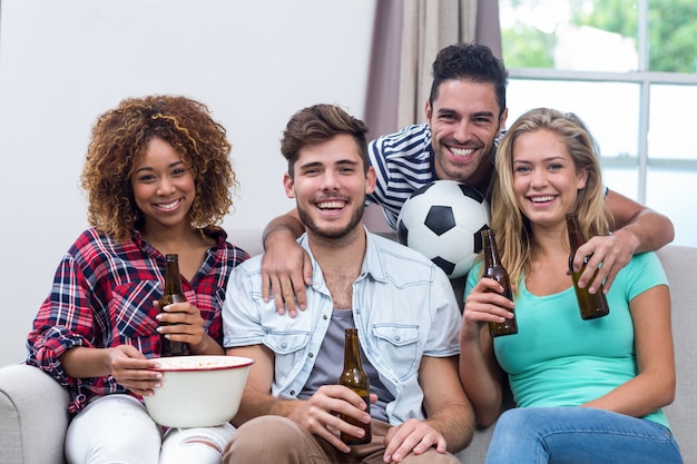 Multiétnicas amigos disfrutando de la cerveza mientras ve un partido de fútbol