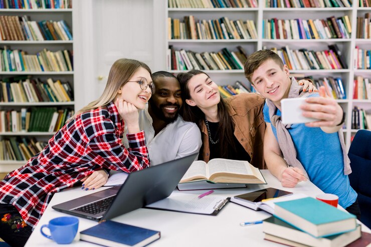 Foto multiétnicas sorridentes estudantes felizes estão estudando na biblioteca, se divertindo durante as férias e fazendo selfie