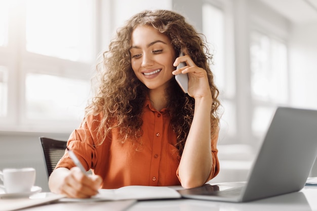 Foto multifascosidade de mulher profissional usando telefone e escrevendo anotações