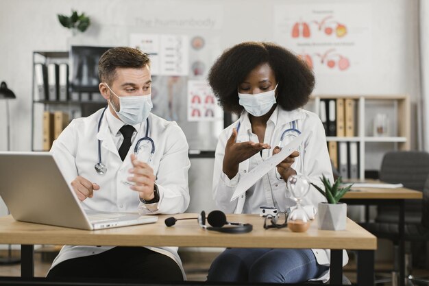 Multikulturelle Ärzte in Gesichtsmasken mit Online-Meeting