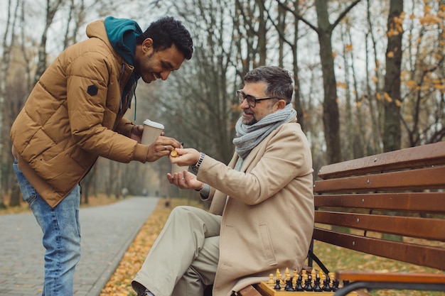 Multikulturelle Freundschaft von Menschen unterschiedlichen Alters Ein Treffen zweier Freunde zum Schachspiel im Park