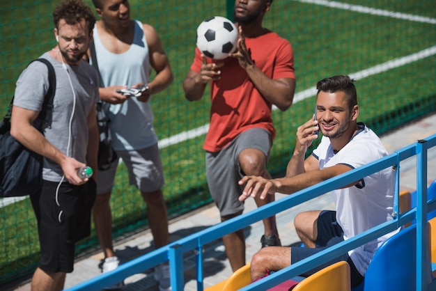 Multikulturelle Fußballmannschaft, die sich vor dem Spiel gemeinsam auf dem Stadion ausruht