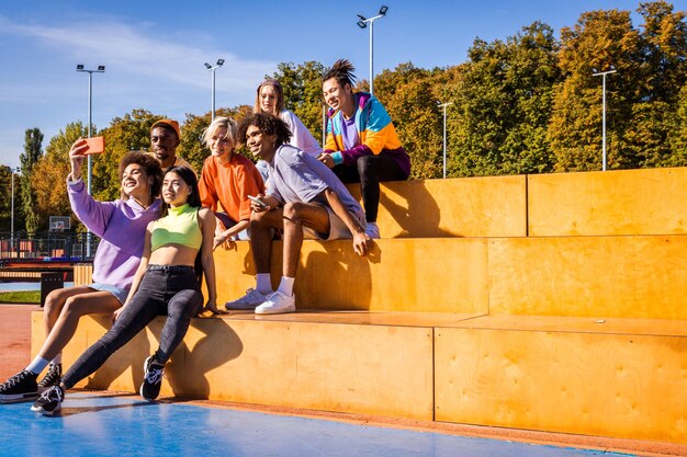 Multikulturelle gruppe junger freunde, die sich im freien verbinden und spaß haben - stilvolle, coole teenager, die sich im urbanen skatepark versammeln