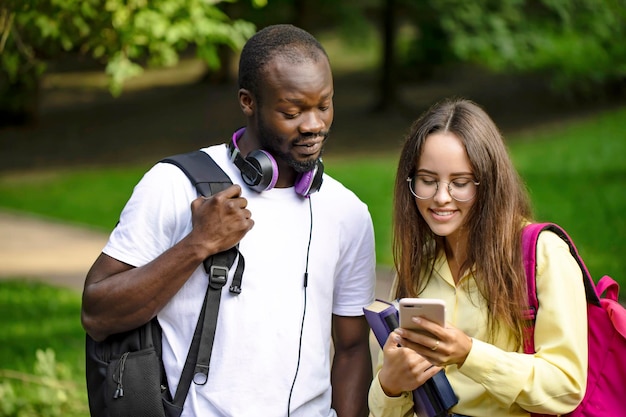 Multikulturelle junge Studenten, die den Newsfeed der Universität per Handy abrufen