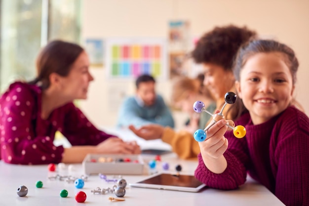 Multikulturelle Schüler mit Lehrern im Klassenzimmer, die molekulares Modell im naturwissenschaftlichen Unterricht studieren