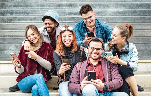 Multikulturelle städtische Freunde, die sich am städtischen Ort am Handy amüsieren