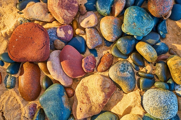 Múltiples colores de piedras lisas lavadas en la orilla arenosa