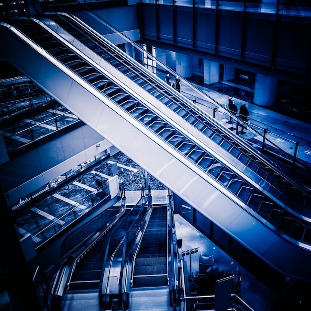 Los múltiples pasos y direcciones de una escalera mecánica en el moderno centro comercial, fondo blanco y negro