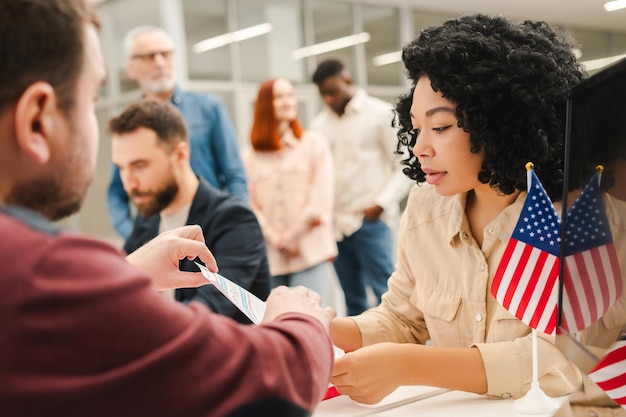 Foto multiracial group of people african american woman sitting at registration table filling out ballot