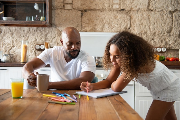 Multirassische Familie, die ihre Zeit in der Küche des Hauses teilt