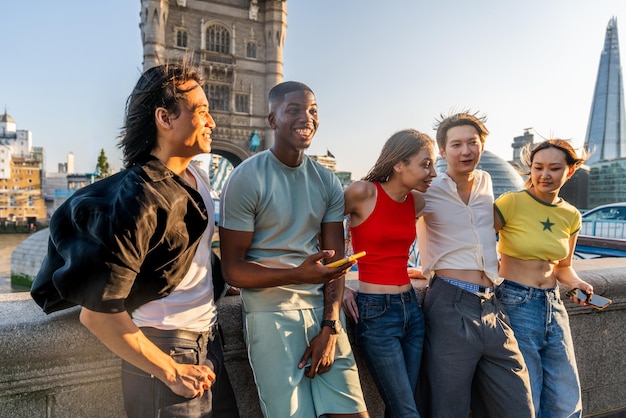Foto multirassische gruppe glücklicher junger freunde, die sich in der stadt london verbinden, multiethnische teenager, studenten, die sich in der gegend von tower bridge treffen und spaß haben, großbritannien konzepte über jugendlebensstil, reisen und tourismus