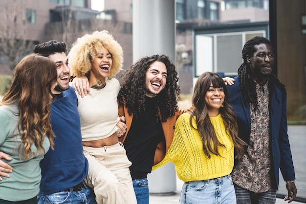 Multirassische Gruppe von Freunden, die zusammen spazieren gehen und sich amüsieren, Millennials, die im städtischen Kontext lächeln und lachen, soziale Vielfalt von Menschen aus der ganzen Welt