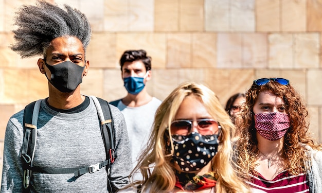 Multirracial caminando cerca de la pared en el contexto urbano de la ciudad - Centrarse en el chico afroamericano izquierdo