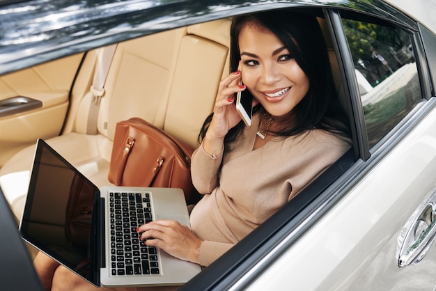 Multitasking-Geschäftsfrau, die im Taxi arbeitet