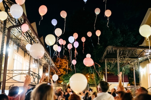 Multitud arrojando globos de colores al cielo por la noche durante el festival