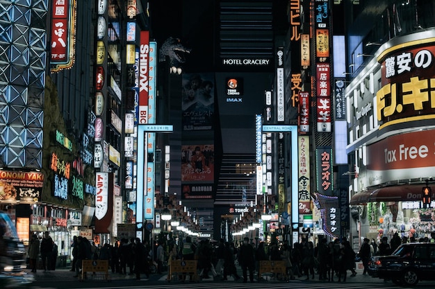 multitud caminando por la calle de la ciudad contra edificios modernos iluminados por la noche