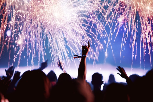 Multitud en un concierto de música contra fuegos artificiales durante la noche