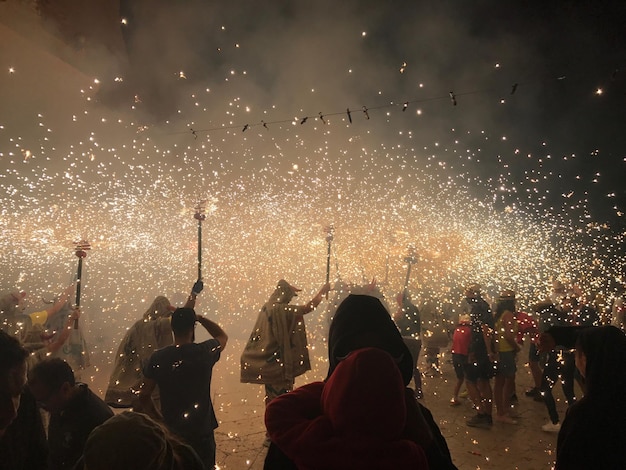 Multitud con espectáculo de fuegos artificiales por la noche