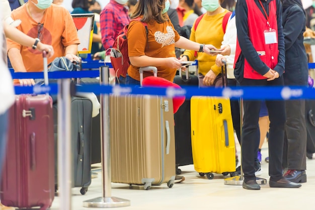 Multitud de personas con equipaje esperando en fila en el aeropuerto durante la cuarentena del coronavirus