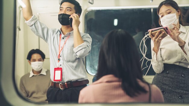 Multitud de personas con máscara facial en un viaje en tren subterráneo público abarrotado