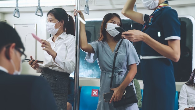 Multitud de personas con máscara facial en un viaje en tren subterráneo público abarrotado