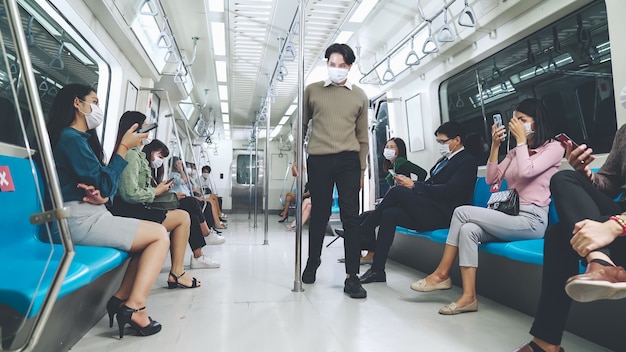Multitud de personas con máscara facial en un viaje en tren subterráneo público abarrotado