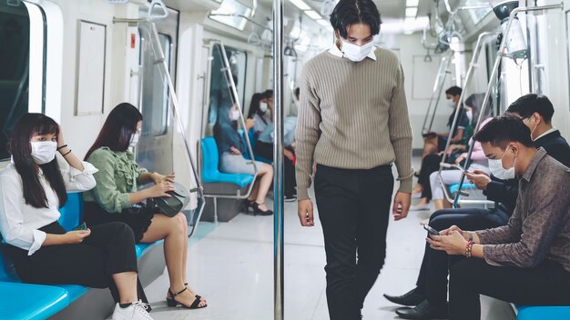 Multitud de personas con máscara facial en un viaje en tren subterráneo público abarrotado