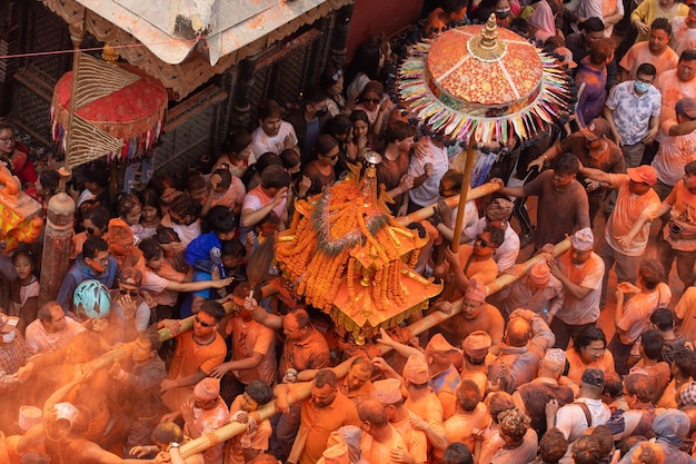 Una multitud de personas se reúnen en un festival con polvo de color naranja en los pies.