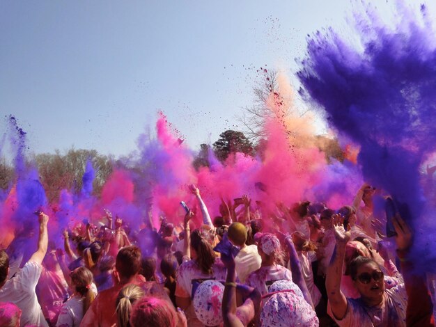 La multitud soplando polvos coloridos durante el festival de Holi contra el cielo