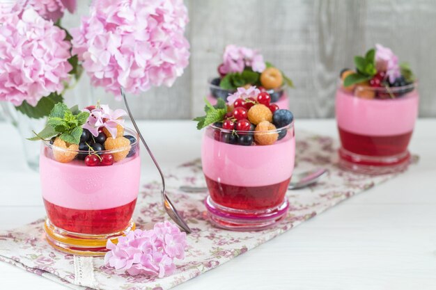 Multivitamin Sommerbeere köstliche Panacotta Süßes Essen mit Himbeeren Blaubeeren Johannisbeeren Croutons und mintrosa Hortensienstrauß heller Hintergrund