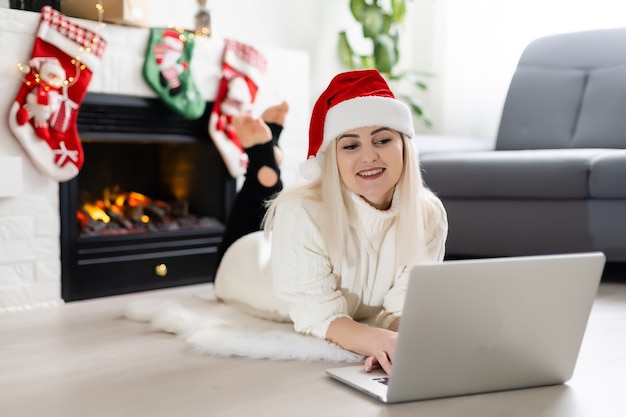 El mundo entero en un solo toque. Primer plano de la hermosa joven mujer de cabello rubio trabajando en la computadora portátil y sonriendo fondo de Navidad